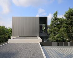 the house is surrounded by trees and bushes, with its roof made out of concrete