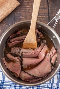 a pot filled with meat sitting on top of a wooden table