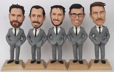 five figurines of men in suits and ties are standing on wooden bases with their hands behind their backs