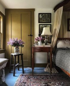 a bed sitting in a bedroom next to a table with flowers on it