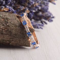 a close up of a ring on a piece of wood with flowers in the background