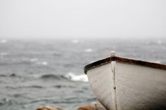 a boat sitting on top of a beach next to the ocean with waves in the background