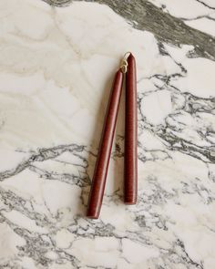 two wooden sticks sitting on top of a marble counter next to each other and one is brown