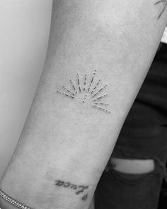 a person's arm with a small starburst tattoo on the left forearm