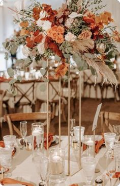 an elegant centerpiece with orange flowers and greenery