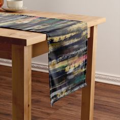 a wooden table topped with a black and yellow striped table runner next to a bowl of fruit