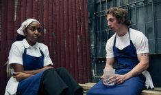 two people sitting next to each other wearing aprons