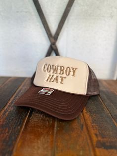 Brown threaded "COWBOY HAT" embroidered on a Brown & Tan Otto brand foam trucker hat. The perfect accessory to make a bold statement! One size fits all Adjustable snap back Embroidered design Cheap Brown Trucker Hat With Letter Print, Brown Trucker Hat With Embroidered Patch, Brown Flat Bill Trucker Hat With Embroidered Patch, Trucker Hat With Letter Patch And Flat Brim, Brown Embroidered Logo Trucker Hat With Flat Brim, Adjustable Trucker Hat With Embroidered Logo, Trucker Hat With Embroidered Logo And Flat Brim, Trucker Hat With Letter Patch, One Size Fits Most, Trucker Hat With Letter Patch, One Size