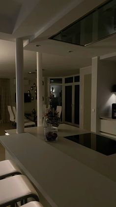 an empty kitchen and living room are seen in this dark lit image from the dining room