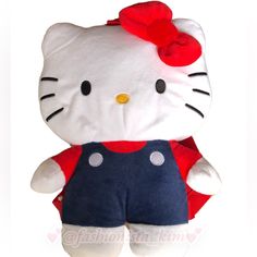 a hello kitty stuffed animal wearing overalls and a red bow on top of it's head