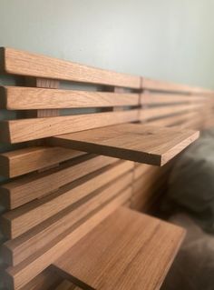 a close up view of a wooden shelf in a room with a bed behind it