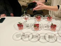 a table topped with wine glasses filled with desserts and garnished with strawberries