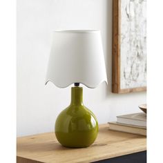 a green lamp sitting on top of a table next to a white shade over it