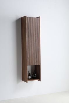 a wall mounted shelf with two bottles on it's sides and a wooden cabinet in the middle