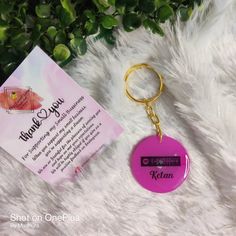 a pink keychain sitting on top of a white fur covered floor next to a card