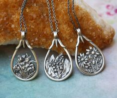 three silver necklaces with flowers on them