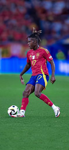 a soccer player with dreadlocks on his head is about to kick the ball