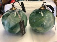 two green glass lamps sitting on top of a white cloth covered table next to each other