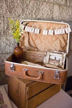 an old suitcase is sitting on top of a table with flowers and pictures in it