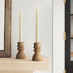 two candles sitting on top of a table next to a mirror