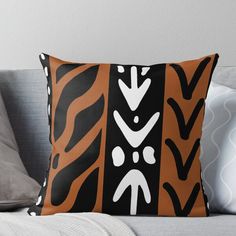 an orange and black pillow with white designs on the front, sitting on a couch