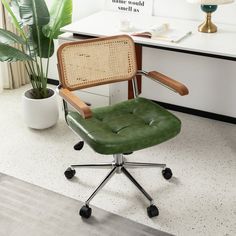 a green office chair sitting on top of a white floor next to a potted plant