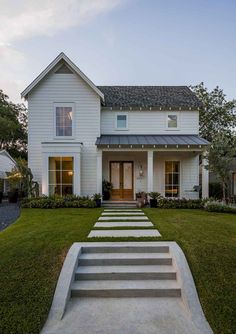 a white house with steps leading up to the front door and windows on each side