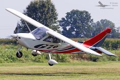 a small red and white plane is flying low to the ground in an open field