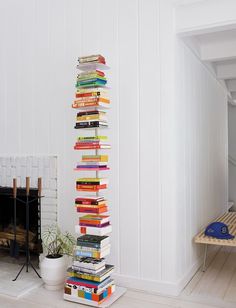 a tall stack of books sitting next to a fireplace