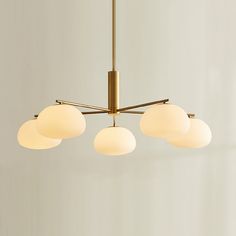 a chandelier with five white balls hanging from it's brass finish fixture