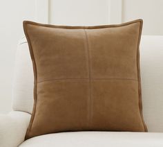 a beige pillow sitting on top of a white couch