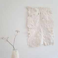 a vase with some flowers in it next to a piece of paper on the wall