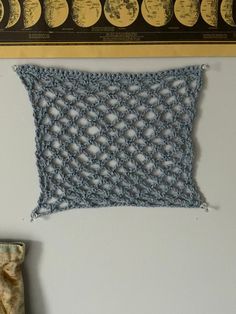 a crocheted piece of cloth hanging on the wall next to a pair of scissors