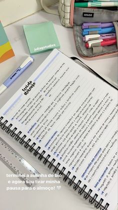 an open notebook sitting on top of a desk next to a pen and pencil holder