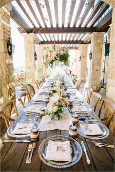 a long table set with plates and place settings for an outdoor dinner party or wedding