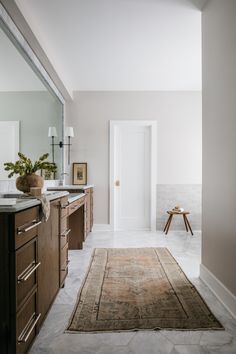 a bathroom with a rug on the floor and a mirror in the wall next to it