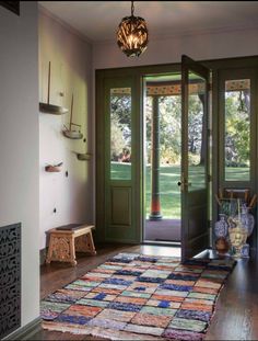 an entryway with green doors and rug on the floor