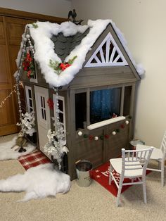 a doll house is decorated for christmas with snow on the roof and decorations around it