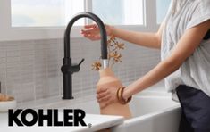 a woman is washing her hands in the kitchen sink with kohler faucet