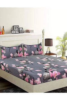 a bed with pink and grey flowers on it