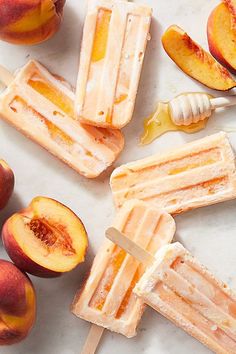 popsicles with peaches and honey sit on a marble surface next to sliced peaches