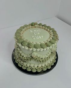 a three layer cake with green icing on a white table