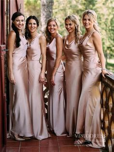 four beautiful women in long dresses posing for a photo on a balcony with trees behind them