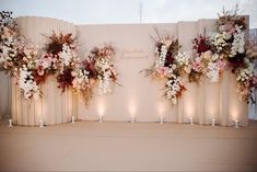 an arrangement of flowers and candles on a wall