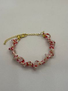 a red and white beaded bracelet on a gold chain