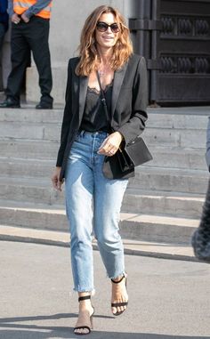 a woman in jeans and heels walking down the street