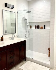 a bathroom with two sinks, a shower and a large mirror on the wall above it