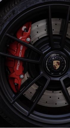 the front wheel of a sports car with red brake pads on it's rim