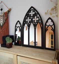 three mirrors are on top of a wooden shelf next to a potted plant and mirror