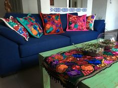 a blue couch with colorful pillows on it and a coffee table in front of it